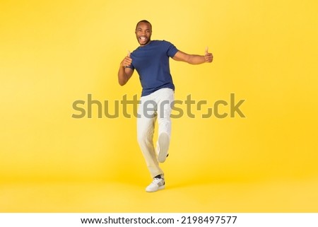 I Like This. Happy African American Male Gesturing Thumbs Up With Both Hands Approving Offer Posing Over Yellow Studio Background. Approval Concept. Full Length Shot