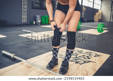 Unrecognizable athletic woman wearing knee pads indoors gym preparing for training Royalty-Free Stock Photo #2198519403