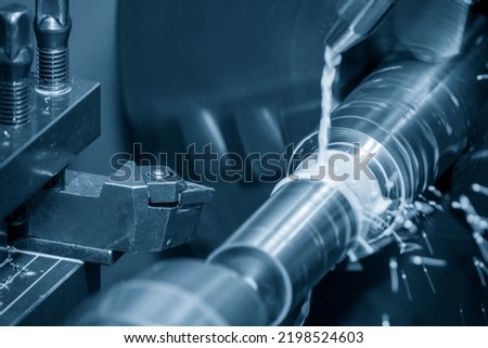 The lathe machine cutting the metal shaft parts with coolant method. The metalworking process by turning machine.