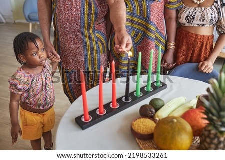 Close-up of man burning candles together with his family while they standing near the table with exotic fruits and celebrating holiday