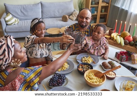 Happy African family of four toasting with drinks during holiday dinner at home