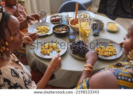 African family in traditional costumes having traditional dinner at table at home, the talking and celebrating holiday
