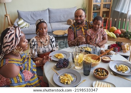 African family of four having holiday dinner at table at home, they celebrating Kwanzaa together with children