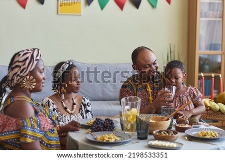 African family of four in national costumes eating traditional food and celebrating Kwanzaa holiday together at home