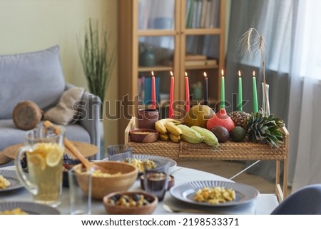 Horizontal image of tray with candles and exotic fruits standing on dining table preparing for celebration of holiday