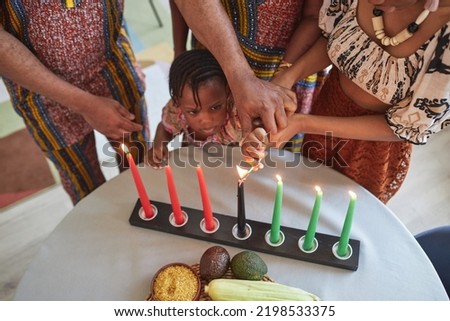 High angle view of African little girl burning candles on table with the help of her family