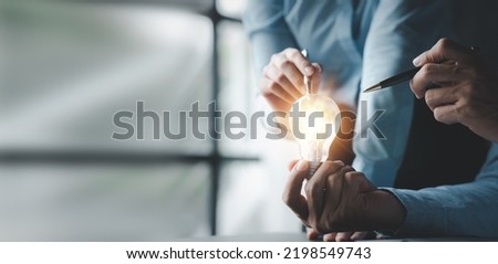 Businessman holds a glowing lamp, Creative new idea. Innovation, brainstorming, strategizing to make the business grow and be profitable. Concept execution, strategy planning and profit management. Royalty-Free Stock Photo #2198549743