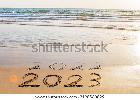 Happy New Year 2023 text on sea beach. Abstract background photo of coming new year 2023 and leaving year of 2022