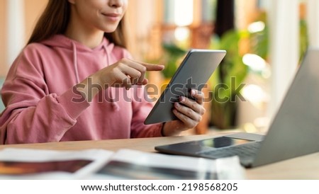 Web based schooling. Female teenager using tablet and laptop for online education, sitting at desk at home, cropped. Positive adolescent girl taking part in webinar, talking to teacher on web Royalty-Free Stock Photo #2198568205