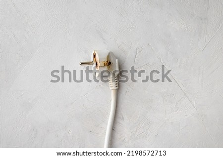 Electric plug after a short circuit, gray concrete background, close-up, copy space, flat lay