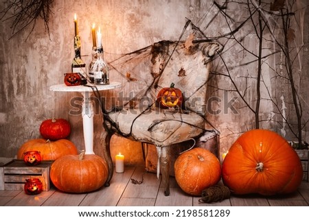 Background decorations for Halloween celebration. A scary composition with Jack's pumpkin and burning candles, spider webs witch's broom with painted Ghost concrete wall. witchcraft, mysticism