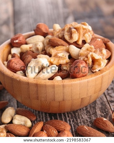 large assortment of nuts like pistachios, hazelnut, pine nut, almonds, pumpkin seeds, sunflower seeds, peanuts, cashew and walnuts. Some nuts are in brown bowls and others in glass jars.