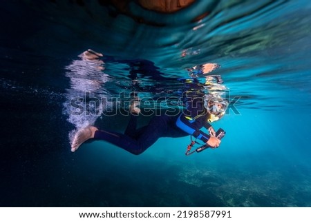 Child snorkeling in an open cave taking pictures with an action camera