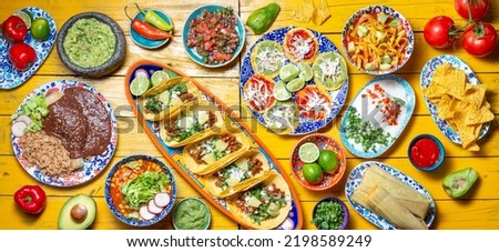 Mexican festive food for independence day - independencia chiles en nogada, tacos al pastor, chalupas pozole, tamales, chicken with mole poblano sauce. Yellow background Royalty-Free Stock Photo #2198589249