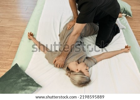 Massage therapist doing massage using oriental techniques Yumeiho for correcting posture of woman's body, top view. Yumeiho therapy Royalty-Free Stock Photo #2198595889
