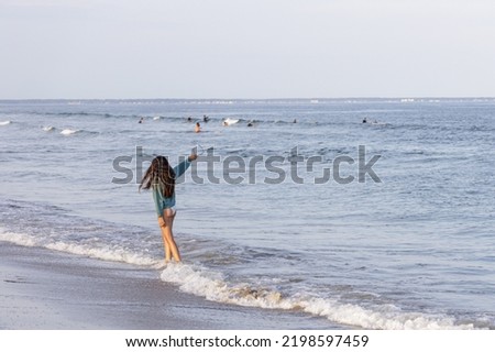 A young lady wearing a bikini is standing at the beach