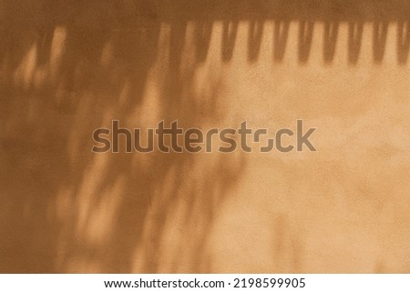Aesthetic sunlight shadow of tree leaves on the neutral orange wall background