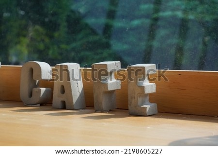 Selective focus, CAFE wooden text word on wooden letters with nature background. Cafe word on the mirror coffee shop cafe