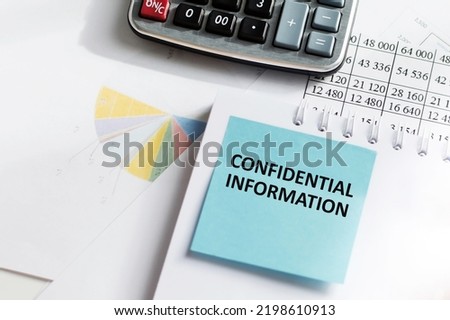confidential information text on a blue card is pasted on a notebook on an office desk
