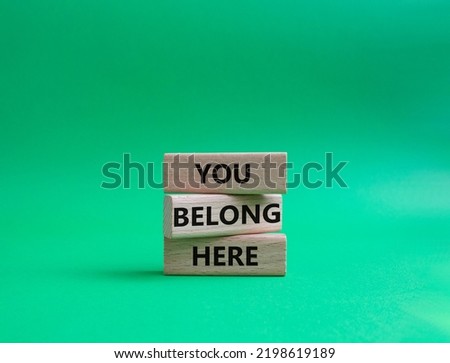 You belong here symbol. Wooden blocks with words You belong here. Beautiful green background. Business and You belong here concept. Copy space.