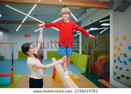Kids doing balance beam gymnastics exercises in gym at kindergarten or elementary school. Children sport and fitness concept Royalty-Free Stock Photo #2198619783