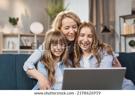 Single Caucasian mother and little children sitting on couch using laptop, family enjoy distant talk by video call, spend time in internet buying, e-commerce users, cartoons or video fun concept