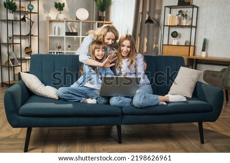 Single Caucasian mother and little children sitting on couch using laptop, family enjoy distant talk by video call, spend time in internet buying, e-commerce users, cartoons or video fun concept