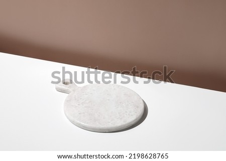 White empty marble board on white table. Blank, still life scene, beige wall, background with plate. Minimal mockup for food. Design Template. Front diagonal view. Royalty-Free Stock Photo #2198628765