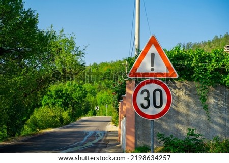 road signs warning of danger and limiting the maximum permissible speed to 30 kilometers per hour, Dangerous part of the road and speed-regulating signs against the background of the green forest.