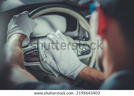 Closeup of Leather Steering Wheel in Modern Vehicle Being Cleaned by Professional Auto Detailer with the Use of Special Fluid-Saturated Wipes. Professional Car Detailing Services Theme. Royalty-Free Stock Photo #2198643403