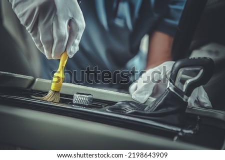 Closeup of Professional Auto Detailing Tool for Interior Cleaning Being Used by Vehicle Detailer to Remove Dust From Controllers Around Automatic Transmission. Royalty-Free Stock Photo #2198643909