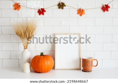 Frame mockup with autumn fall home decor, pumpkins, cup of coffee, candle in cozy home interior. Fall poster design. Halloween or Thanksgiving concept.