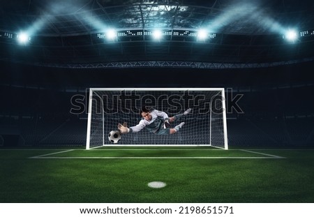 Soccer goalkeeper that makes a great save and avoids a goal during a match at the stadium Royalty-Free Stock Photo #2198651571