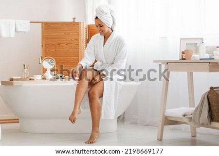 Pretty Woman Shaving Legs Using Safety Razor Sitting In Modern Bathroom At Home, Wearing White Bathrobe. Depilation And Bodycare, Hair Removal Cosmetics Concept Royalty-Free Stock Photo #2198669177