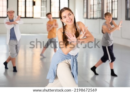 Emotional teenage girl having group dance training in studio, performing dynamic elements Royalty-Free Stock Photo #2198672569