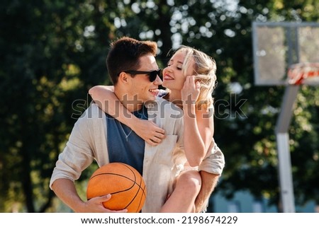 summer holidays, love and people concept - happy young couple with ball having fun on basketball playground