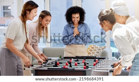 Team building, break and business women playing game in office lounge room having fun and bonding together. Trendy, cool and diversity of creative staff with fun mini table football match activity Royalty-Free Stock Photo #2198684391