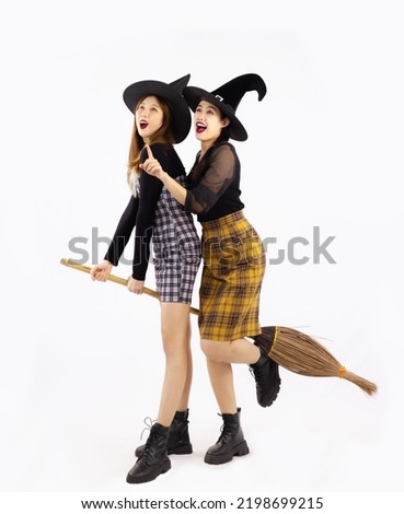 Halloween theme, young asian women in black costume wearing witch hat and holding broomstick posing on white background.