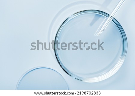Empty round petri dish or glass slide and Pipette on blue background. Mockup for cosmetic or scientific product sample Royalty-Free Stock Photo #2198702833