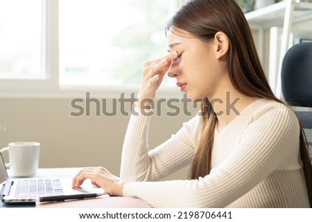 Exhausted, stressed asian young businesswoman working or studying online, massage nose from dry eyes, suffer on hard work while using laptop computer at office home. Overtime job, debt problem people Royalty-Free Stock Photo #2198706441