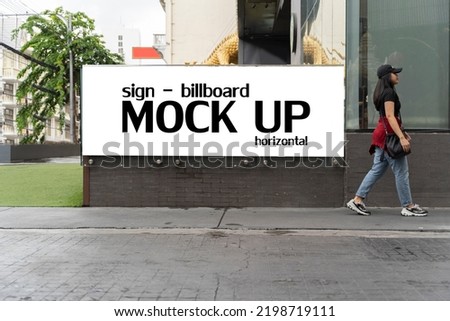 Mock up blank horizontal signboard advertising stand media outdoor with people walking city street building. Empty space for advertising or announcement information.