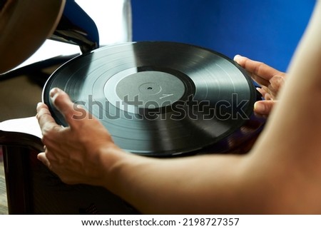  Young woman holding vinyl record over wooden record player. Beautiful girl in vintage dress wants to listen to music on old gramophone. Pretty woman turns on music on gramophone to dance            
