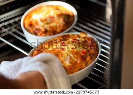 Pulling out two trays with baked omelette from he oven Royalty-Free Stock Photo #2198745673