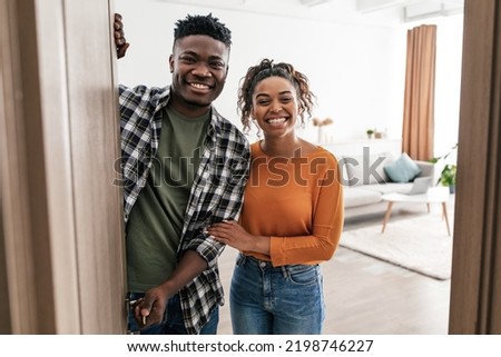 Welcome. Cheerful Black Couple Opening Entry Door Smiling To Camera Posing Standing At Home. Real Estate Buyers Meeting You In Modern Living Room Indoor. New House Ownership Concept Royalty-Free Stock Photo #2198746227