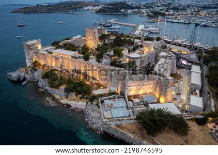 Bodrum bay and ancient castle of Saint Peter at the sunset. Boats floating on calm blue sea. Mountains in the background. Aerial view from drone.