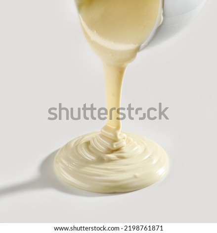 melted white chocolate pouring on white background Royalty-Free Stock Photo #2198761871