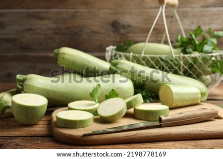 Cut and whole ripe zucchinis on wooden table Royalty-Free Stock Photo #2198778169