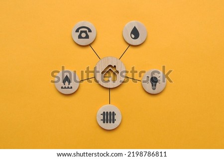 Utility icons on wooden mugs and a house nearby. A symbol of the necessary services in the house Royalty-Free Stock Photo #2198786811