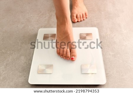 woman's feet getting on a weight scale. weight control. gain weight or lose weight from diet