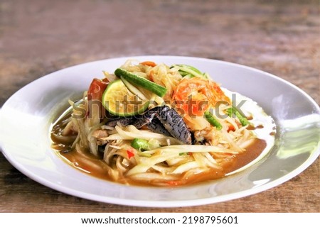 Famous Thai food papaya salad with dried shrimp and salted crab on white plate photo on wooden back ground